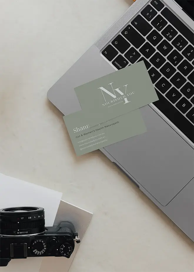 Custom designed Nourished You green business card placed on laptop next to camera gear