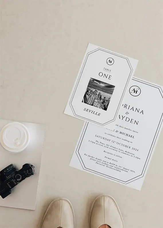 Wedding invitation and table card placed on floor with camera and shoes