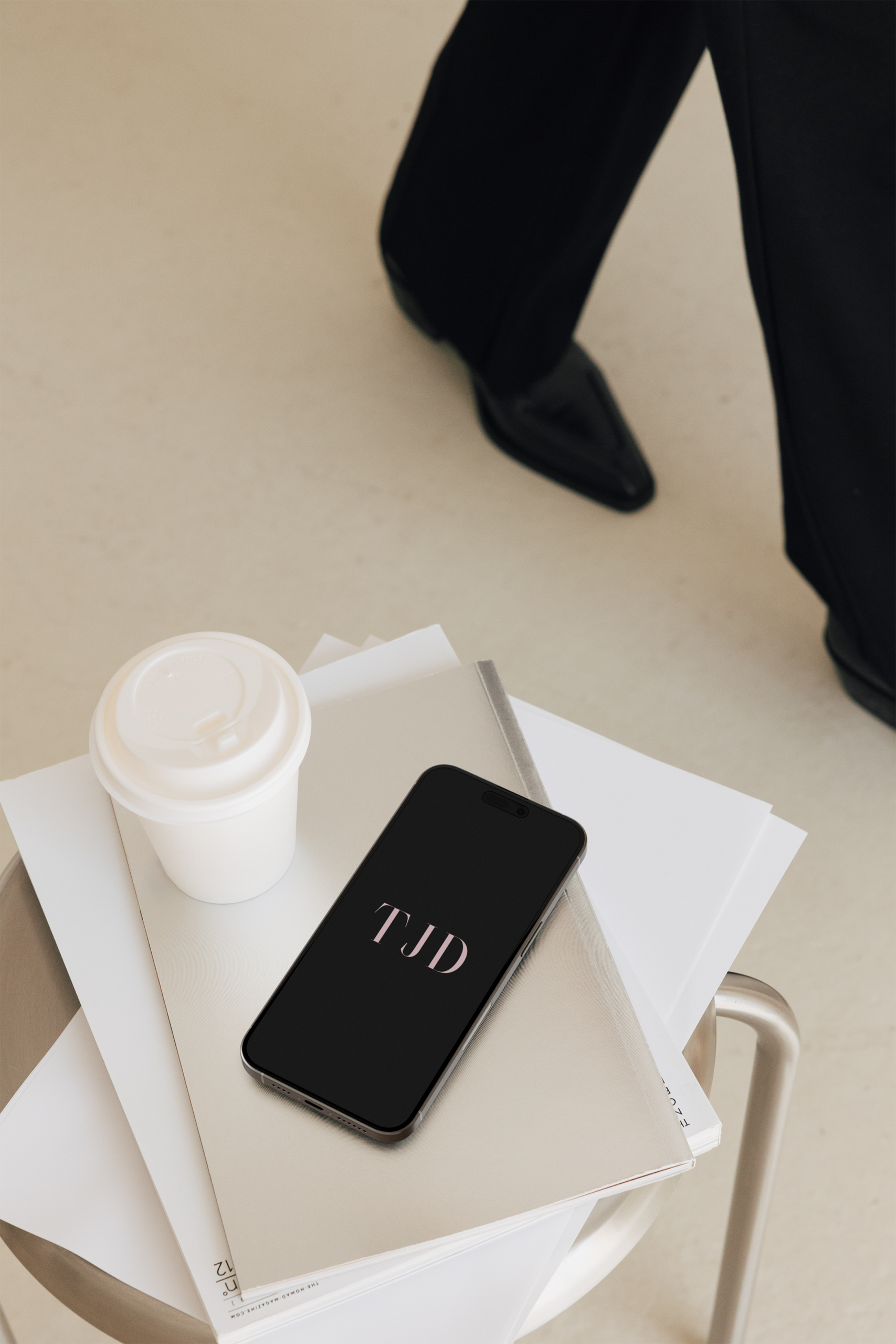 Tina Jenner Designs contact page hero image showing branded materials, coffee cup, and phone with TJD logo on neutral background