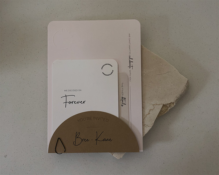 Minimalist wedding invitation suite showing custom wedding stationery design with soft pink card stock, hand-lettered names, and geometric design elements